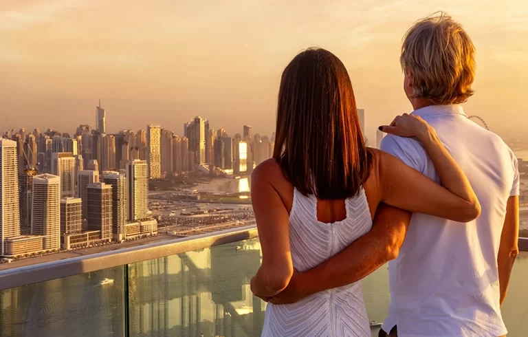 A hugging couple enjoys the panoramic sunset view of the Dubai Marina, UAE
