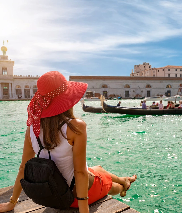 Attractive, female tourist enjoys the view to the Basilica di Santa Maria della Salute and Canale Grande in Venice, Italy