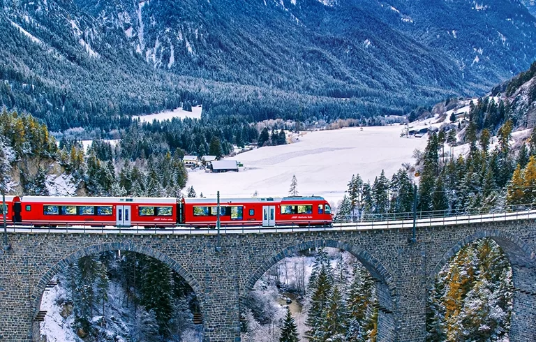 Aerial view of Train passing through famous mountain in Filisur, Switzerland. Landwasser Viaduct world heritage with train express in Swiss Alps snow winter scenery.